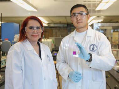 Professor Gisele Azimi stands next to Jiakai (Kevin) Zhang, who holds a solution containing metal nitrates and tributyl phosphate complexes (photo by Safa Jinje)