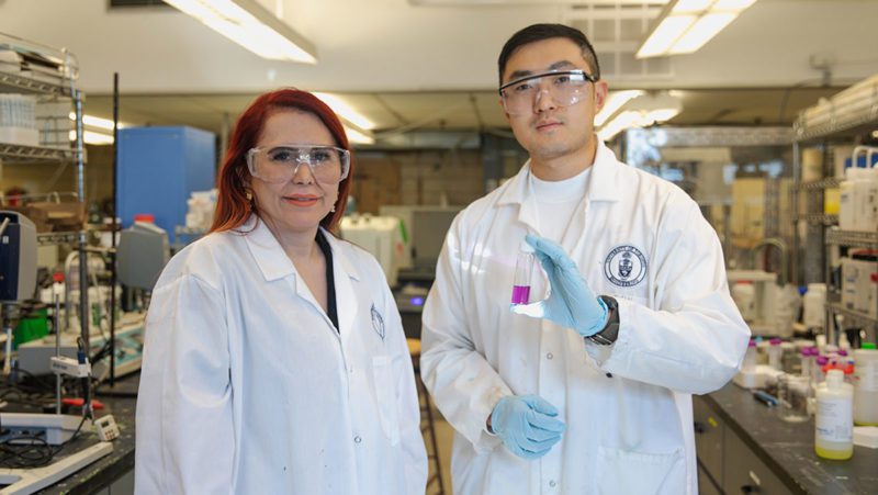 Professor Gisele Azimi stands next to Jiakai (Kevin) Zhang, who holds a solution containing metal nitrates and tributyl phosphate complexes (photo by Safa Jinje)