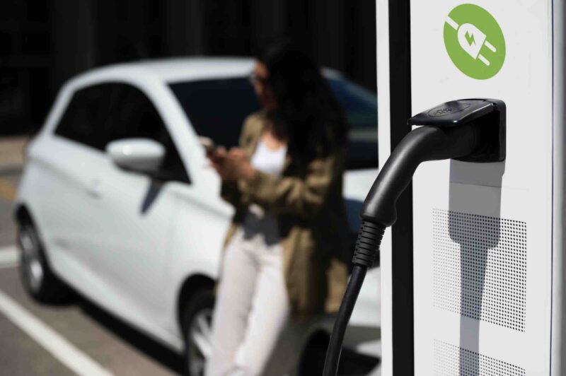 woman charging EV, free pik